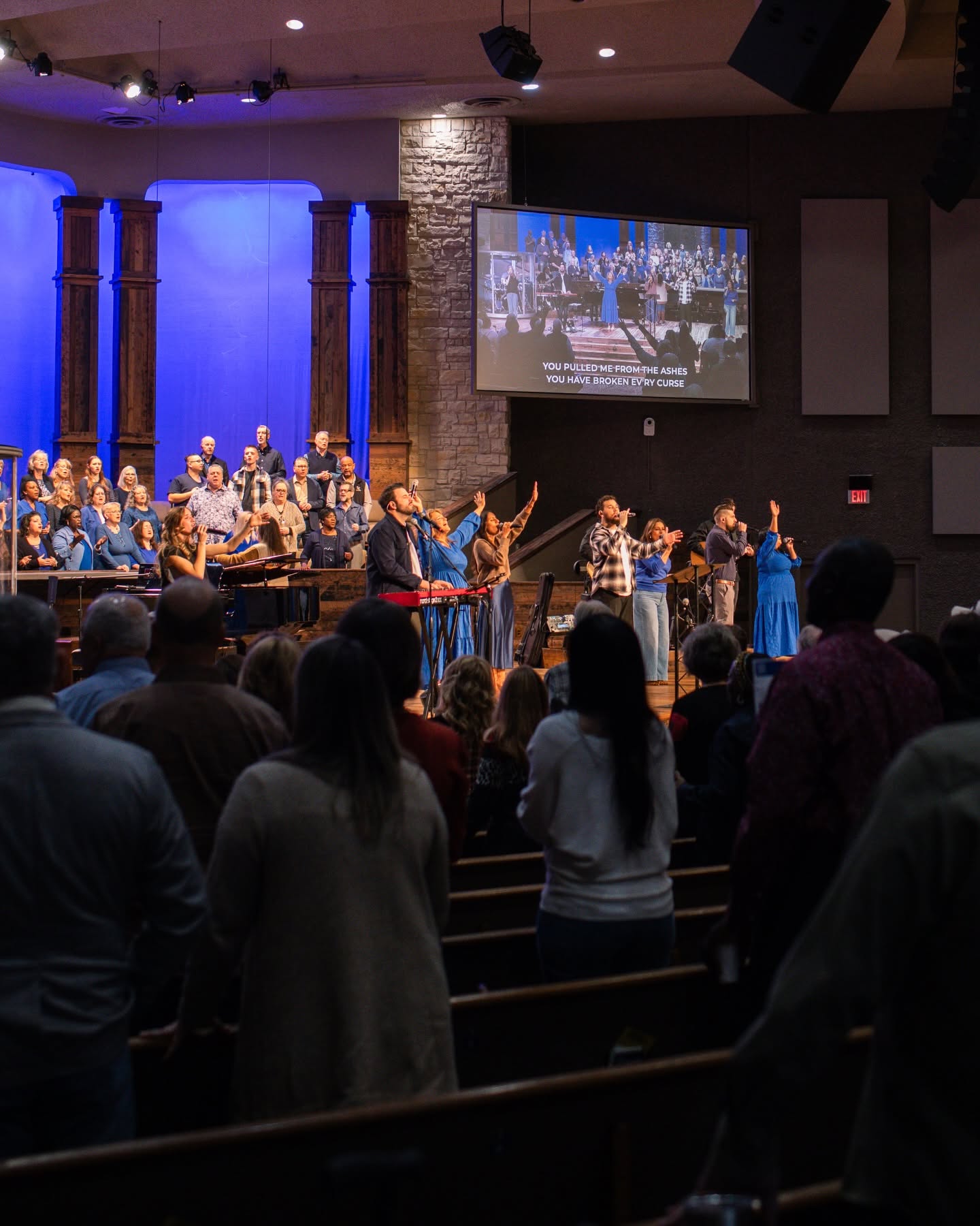 A multi-ethnic congregation worshipping together with the worship team and choir leading from the platform